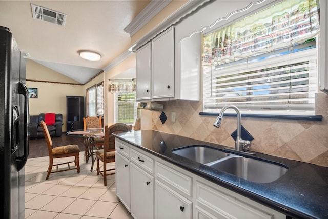 kitchen with white cabinetry, dark countertops, black fridge with ice dispenser, visible vents, and a sink