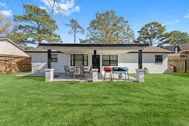 back of house featuring brick siding, fence, and a lawn