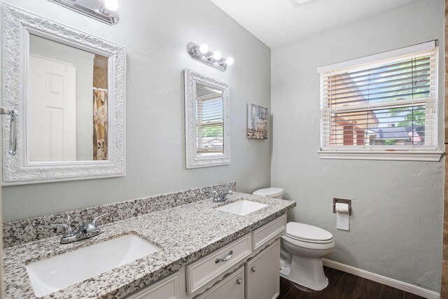 bathroom with a sink, toilet, wood finished floors, and baseboards
