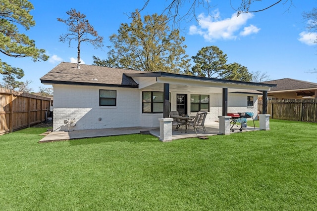 back of property featuring brick siding, a patio, a fenced backyard, and a lawn