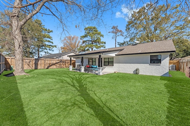 rear view of property with a yard, a fenced backyard, central AC unit, and brick siding