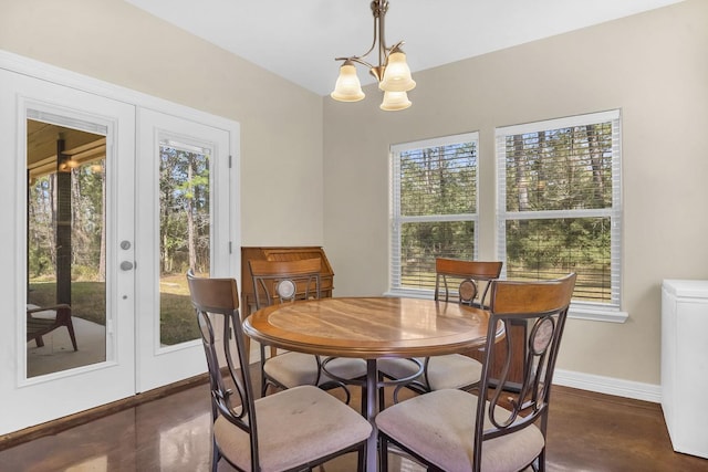dining area with finished concrete floors, an inviting chandelier, baseboards, and a wealth of natural light
