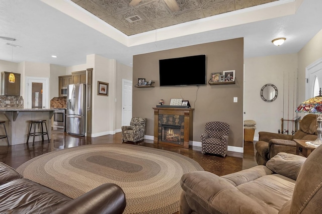 living room with visible vents, a raised ceiling, a fireplace, and dark wood finished floors