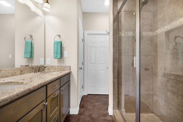 full bath with a shower stall, double vanity, baseboards, and a sink