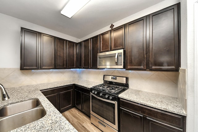 10330 Douglas Fir Villa Ave, Houston, TX 77044 - kitchen with appliances with stainless steel finishes, a sink, dark brown cabinetry, backsplash, and light stone counters