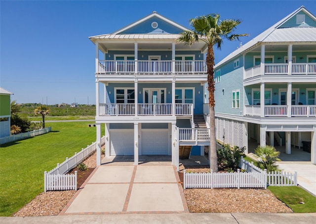 view of front facade featuring concrete driveway, a balcony, fence private yard, a front yard, and a garage