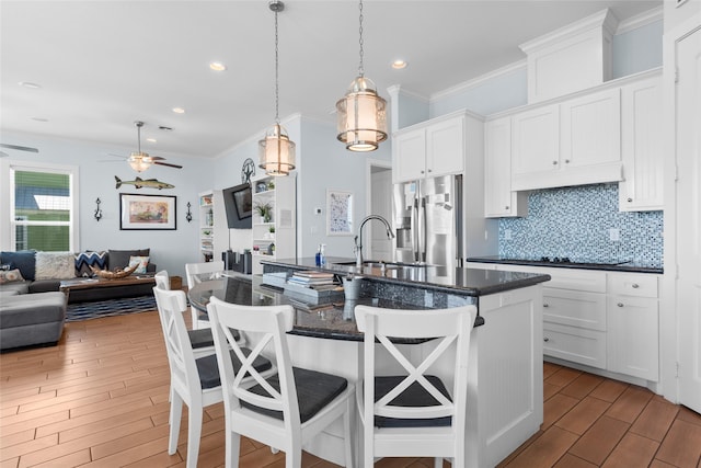 kitchen with stainless steel fridge, a sink, ornamental molding, open floor plan, and wood finished floors