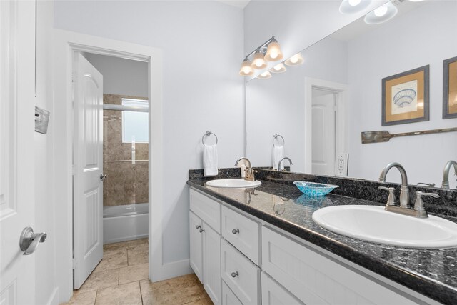 bathroom with a sink, baseboards, double vanity, and shower / washtub combination