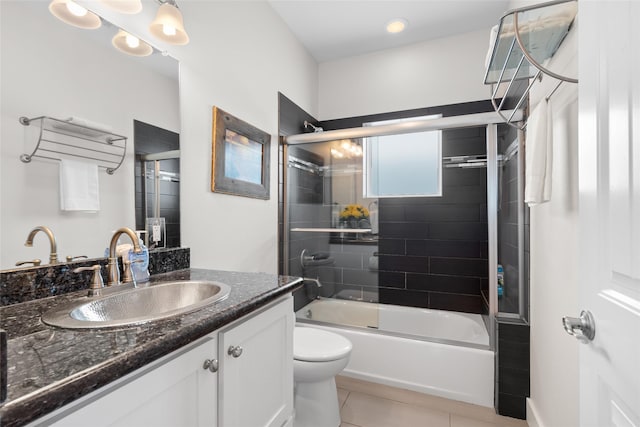 bathroom featuring combined bath / shower with glass door, toilet, tile patterned flooring, and vanity