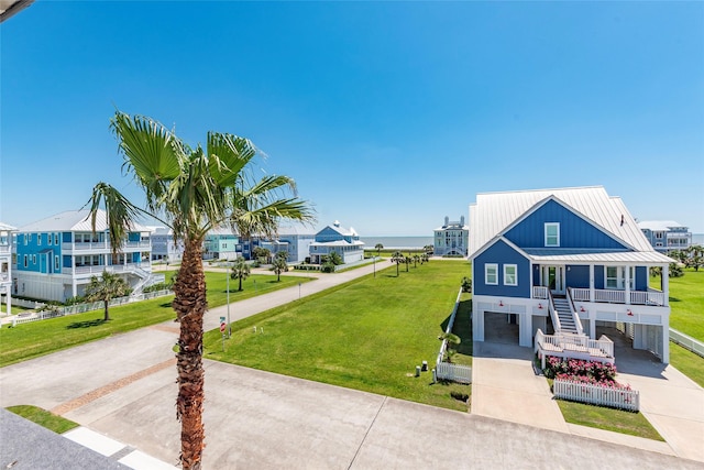 coastal home with a porch, an attached garage, metal roof, stairway, and concrete driveway