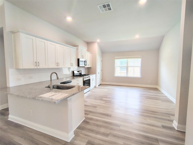 601 Greystone Ln, Angleton, TX 77515 - kitchen featuring appliances with stainless steel finishes, a sink, vaulted ceiling, light stone countertops, and white cabinets