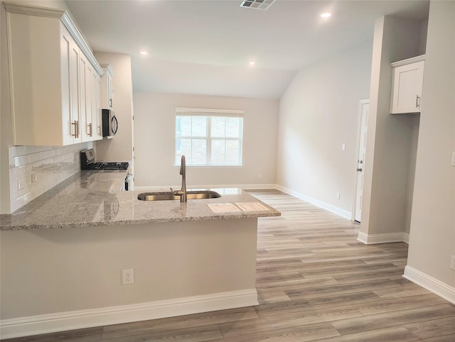 601 Greystone Ln, Angleton, TX 77515 - kitchen featuring a sink, stainless steel appliances, a peninsula, light stone counters, and light wood-style flooring