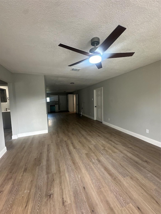 unfurnished living room featuring a ceiling fan, wood finished floors, a textured ceiling, and baseboards
