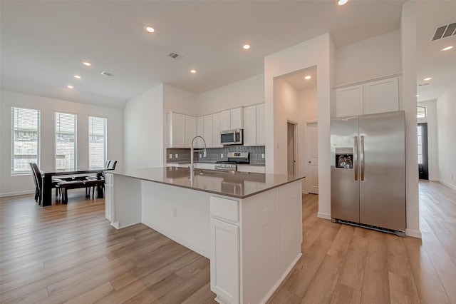 kitchen with stainless steel appliances, visible vents, a sink, and light wood-style flooring
