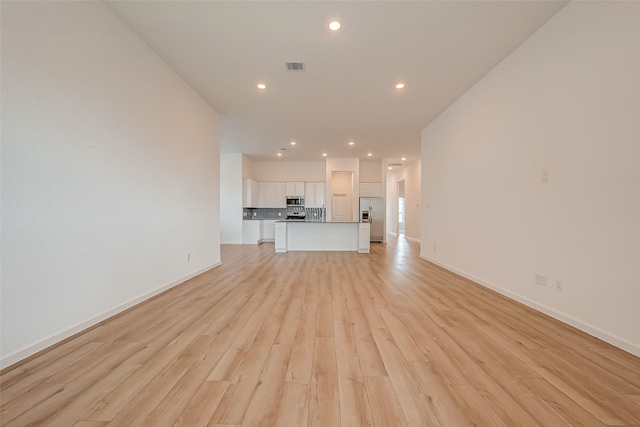 unfurnished living room featuring light wood finished floors, baseboards, visible vents, and recessed lighting