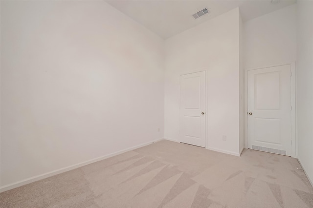 unfurnished room featuring light carpet, high vaulted ceiling, visible vents, and baseboards