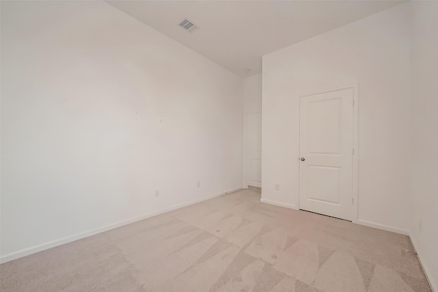 unfurnished room with visible vents, baseboards, and light colored carpet