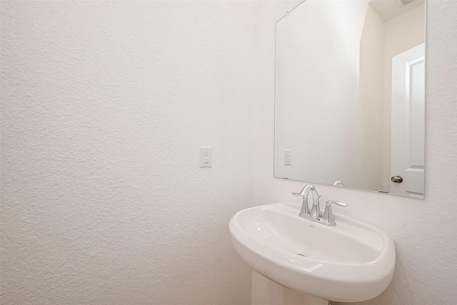 bathroom with a textured wall and a sink