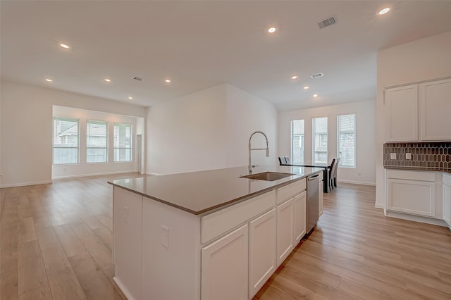 kitchen featuring stainless steel dishwasher, light wood-style floors, visible vents, and a sink
