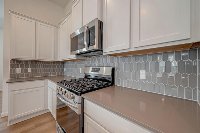 kitchen featuring light wood-style floors, white cabinetry, backsplash, and appliances with stainless steel finishes