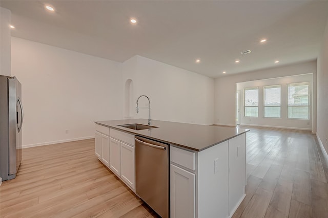 kitchen featuring white cabinets, a sink, an island with sink, light wood finished floors, and stainless steel appliances