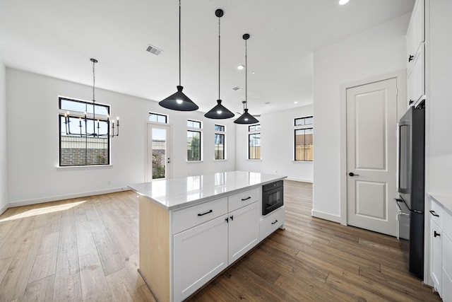 kitchen featuring a wealth of natural light, a center island, hardwood / wood-style floors, and freestanding refrigerator