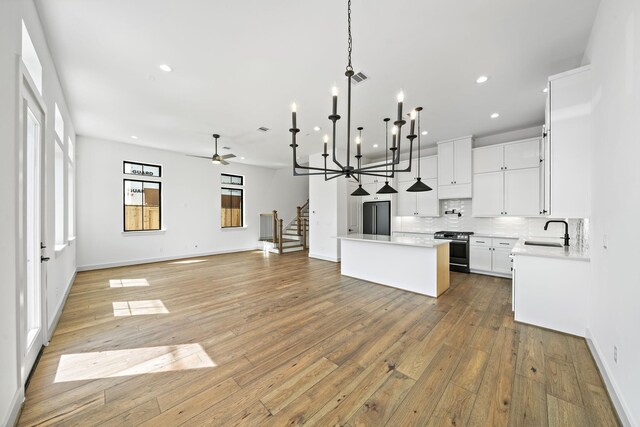 kitchen featuring recessed lighting, black fridge, gas stove, a sink, and open floor plan