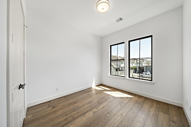 spare room featuring visible vents, baseboards, and wood finished floors