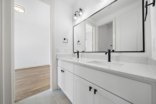 full bath featuring double vanity, a sink, tile patterned flooring, and baseboards