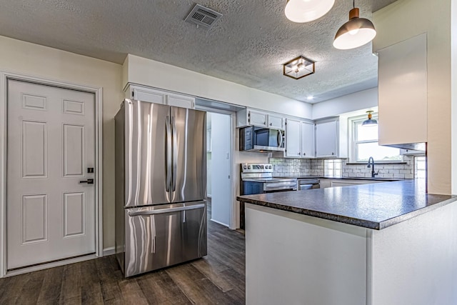 652 E Taylor Lake Cir, Livingston, TX 77351 - kitchen featuring dark wood-style flooring, a peninsula, visible vents, stainless steel appliances, and a sink