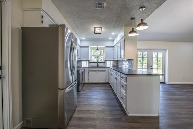 652 E Taylor Lake Cir, Livingston, TX 77351 - kitchen with dark wood-style flooring, a peninsula, freestanding refrigerator, white cabinets, and visible vents