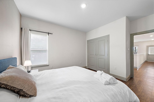 bedroom with baseboards, recessed lighting, wood finished floors, and a closet