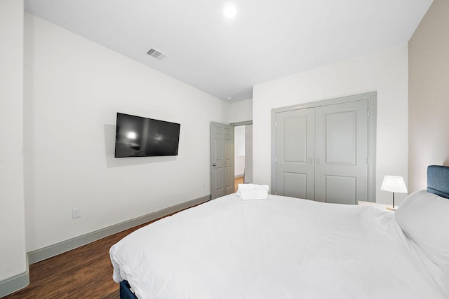 bedroom with a closet, visible vents, wood finished floors, and baseboards