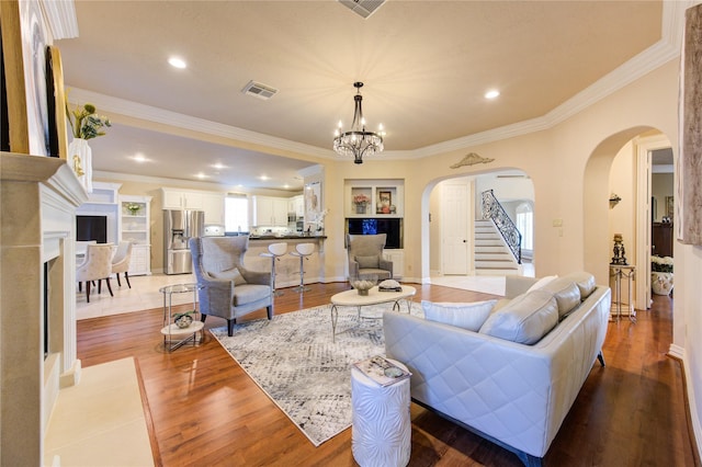 living room featuring wood finished floors, visible vents, plenty of natural light, and arched walkways