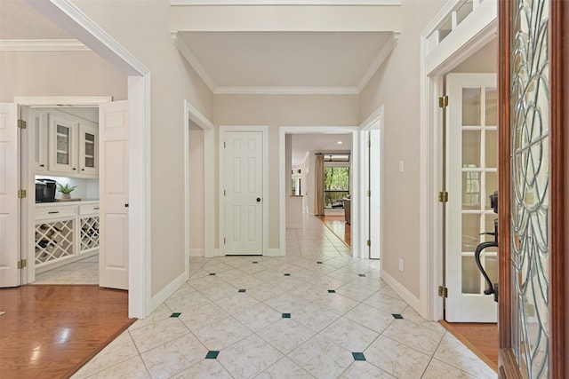hallway with light tile patterned floors, baseboards, and ornamental molding