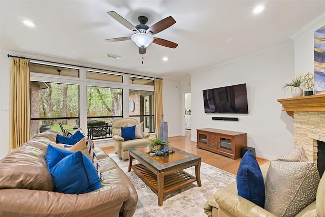 living area featuring visible vents, ceiling fan, a stone fireplace, crown molding, and wood finished floors