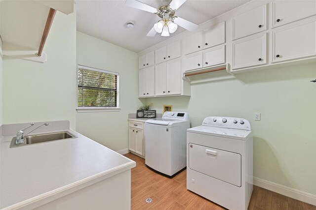 clothes washing area featuring a ceiling fan, light wood-style floors, independent washer and dryer, cabinet space, and a sink