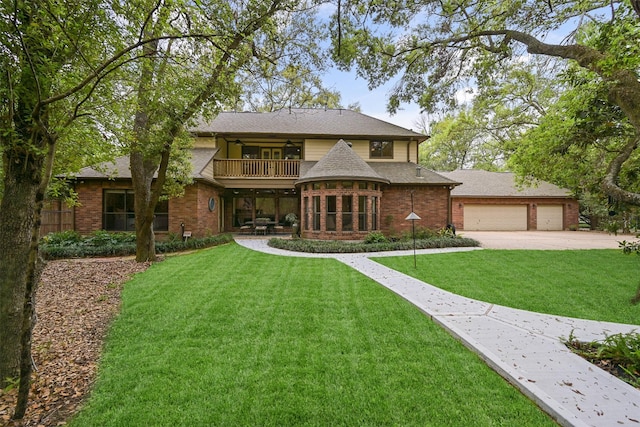 view of front facade featuring roof with shingles, a balcony, a front yard, brick siding, and ceiling fan