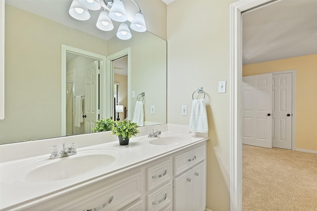 bathroom with a sink, baseboards, double vanity, and a chandelier