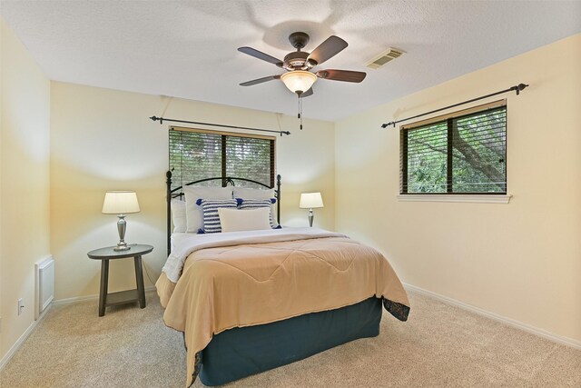 bedroom featuring ceiling fan, a textured ceiling, visible vents, carpet flooring, and baseboards