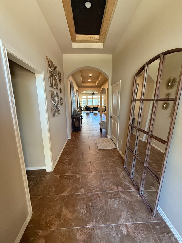 29046 Davenport Dr, Katy, TX 77494 - hall featuring baseboards, arched walkways, a tray ceiling, and stone finish floor