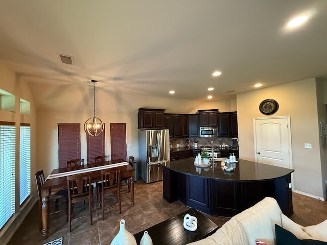 29046 Davenport Dr, Katy, TX 77494 - kitchen with dark brown cabinetry, an island with sink, stainless steel appliances, decorative backsplash, and visible vents