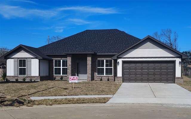 single story home featuring brick siding, an attached garage, driveway, and roof with shingles