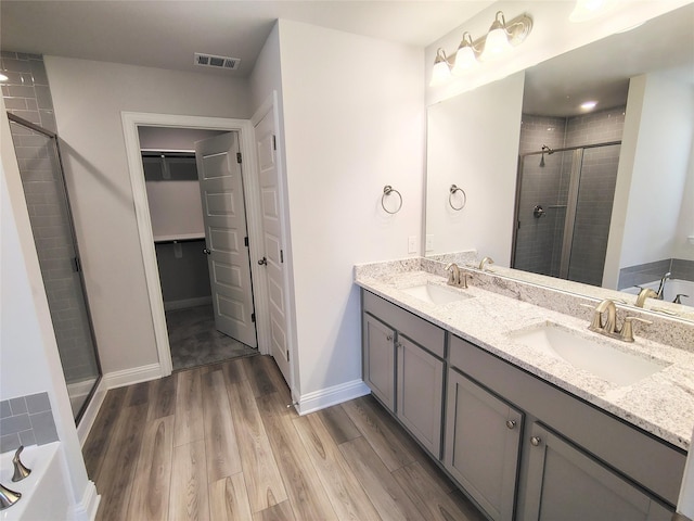 full bath featuring a sink, visible vents, a stall shower, and wood finished floors