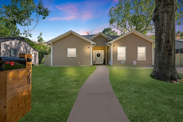 ranch-style house with a yard and fence