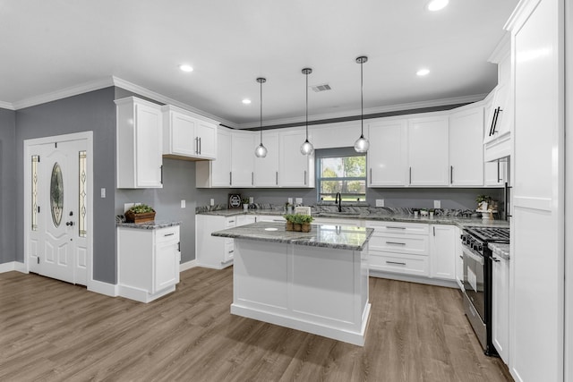 kitchen featuring gas range oven, ornamental molding, light stone counters, visible vents, and a sink