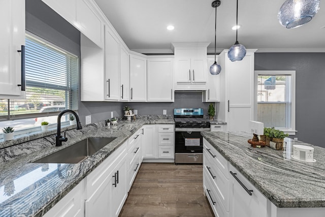 kitchen with plenty of natural light, white cabinets, gas range, under cabinet range hood, and a sink