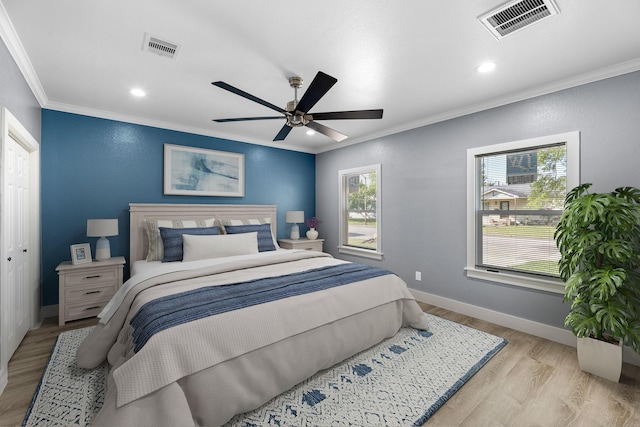 bedroom with visible vents, baseboards, ornamental molding, and light wood-style flooring