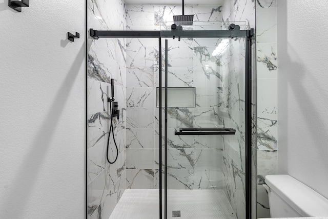 bathroom featuring a marble finish shower and toilet