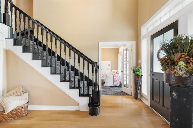 foyer entrance featuring baseboards, stairway, a high ceiling, and wood finished floors
